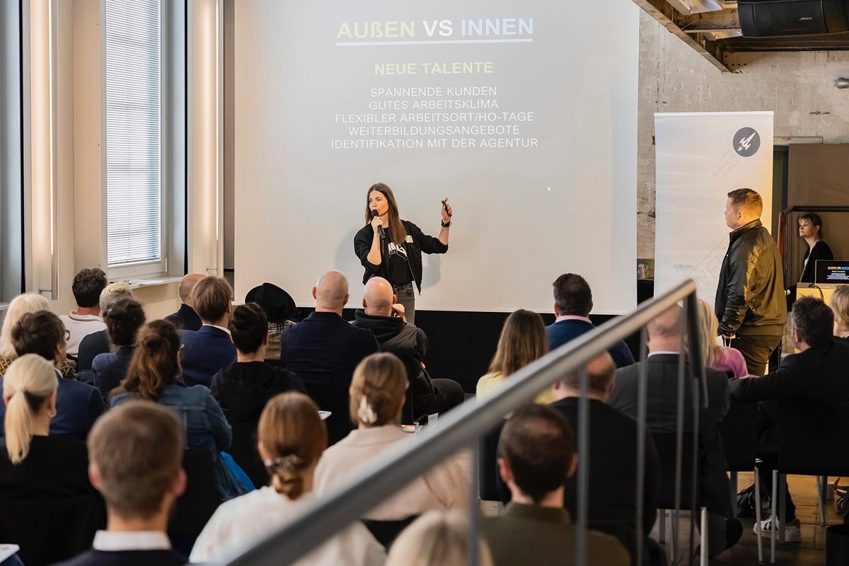 Andrea Foth speaking on stage at a business keynote.