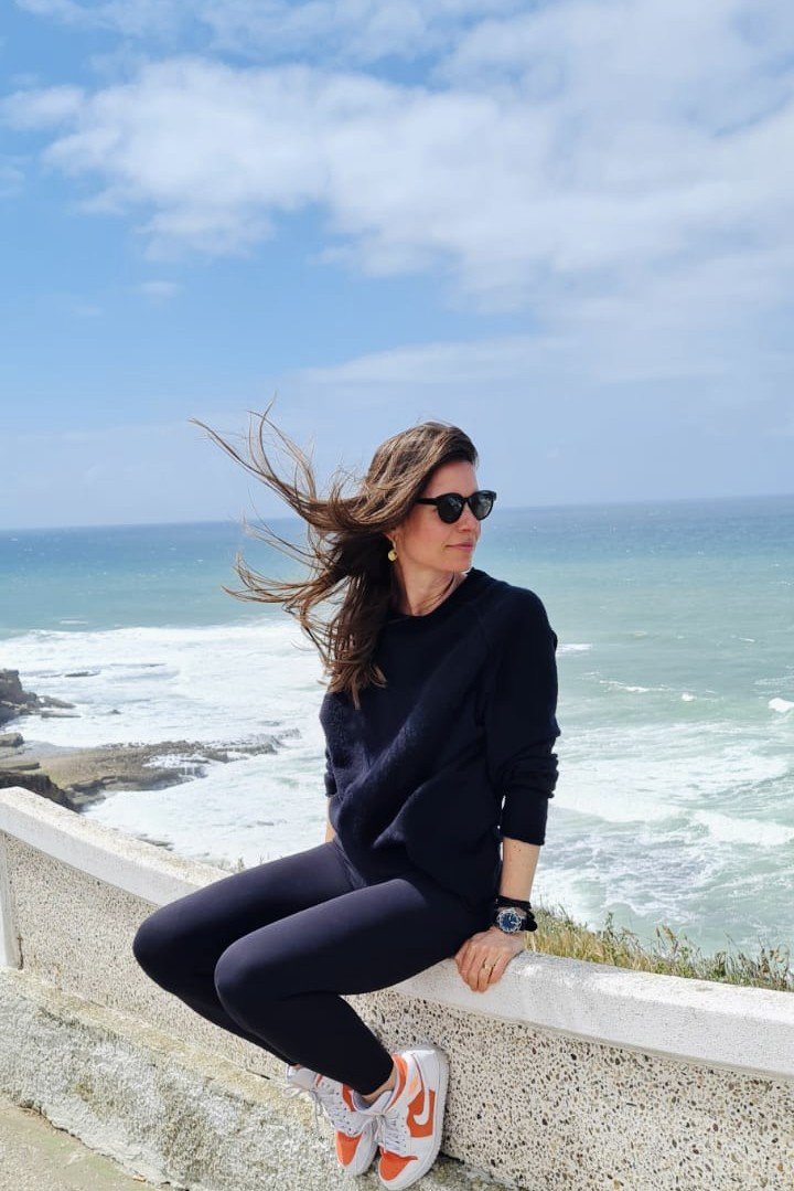 Andrea Foth sitting on a seawall, looking out over the ocean.